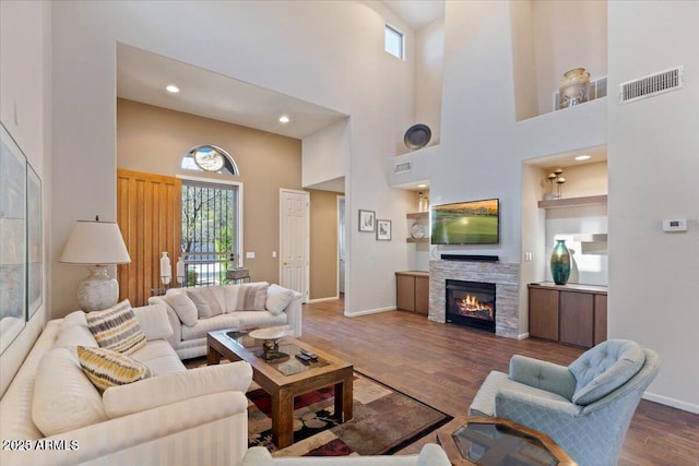 living room featuring a fireplace, a towering ceiling, and dark hardwood / wood-style floors