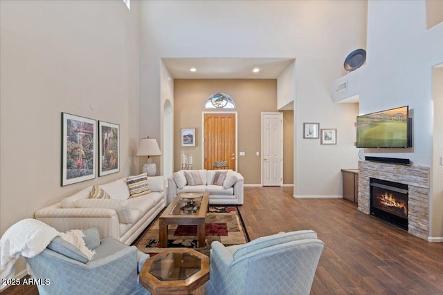 living room with a fireplace, a high ceiling, and dark wood-type flooring