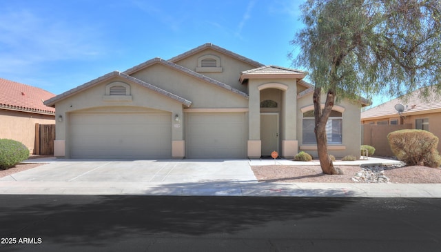 mediterranean / spanish house featuring concrete driveway, an attached garage, fence, and stucco siding