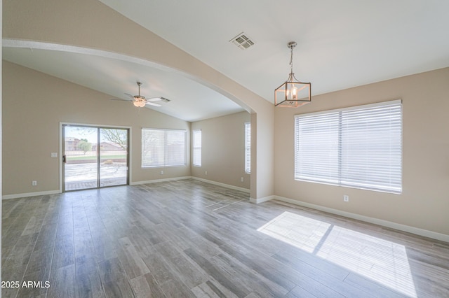 unfurnished room with arched walkways, vaulted ceiling, wood finished floors, and visible vents