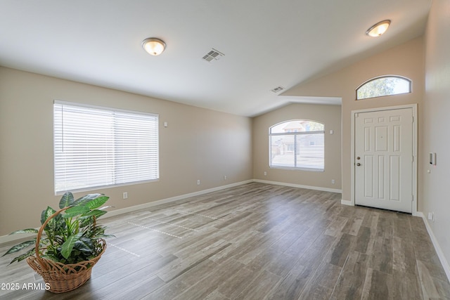 foyer featuring lofted ceiling, visible vents, baseboards, and wood finished floors