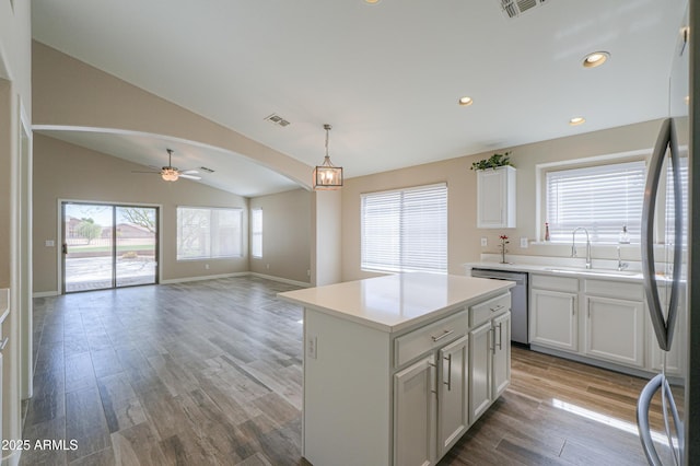 kitchen with a center island, arched walkways, stainless steel appliances, light countertops, and open floor plan