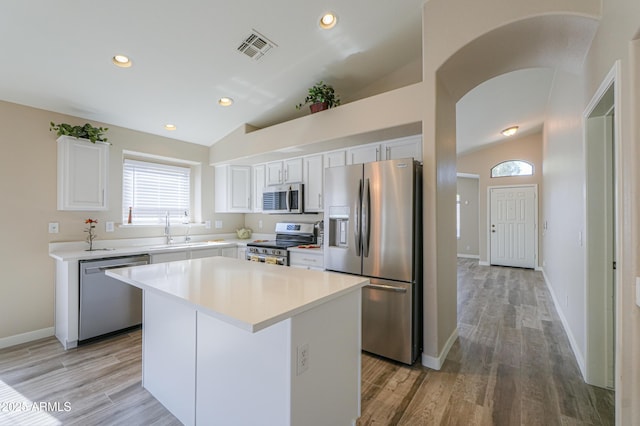 kitchen featuring white cabinetry, stainless steel appliances, light countertops, and a center island