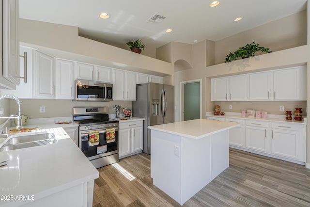 kitchen featuring a sink, a kitchen island, visible vents, light countertops, and appliances with stainless steel finishes