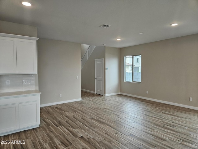 3390 S 180th Ln, Goodyear, AZ 85338 - unfurnished living room with wood finished floors, recessed lighting, baseboards, and stairs