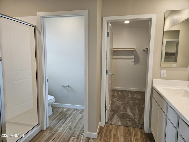 3390 S 180th Ln, Goodyear, AZ 85338 - bathroom featuring baseboards, wood finished floors, a stall shower, a spacious closet, and toilet