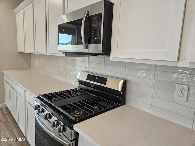 3390 S 180th Ln, Goodyear, AZ 85338 - kitchen featuring stainless steel appliances, white cabinets, light countertops, tasteful backsplash, and light wood-type flooring