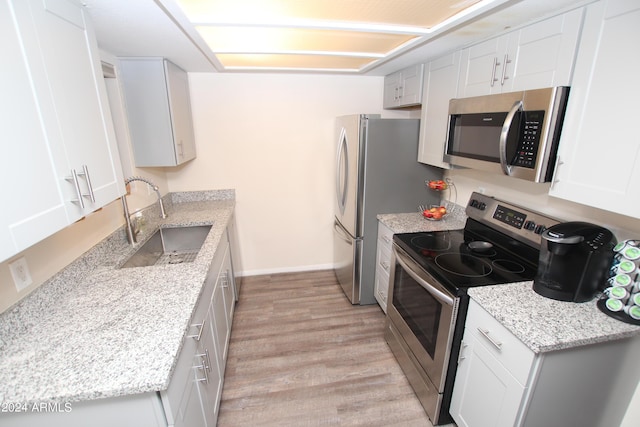 3119 W Cochise Dr Unit 106, Phoenix, AZ 85051 - kitchen featuring appliances with stainless steel finishes, a sink, light wood finished floors, baseboards, and light stone countertops