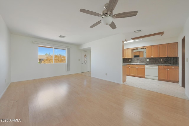 unfurnished living room featuring visible vents, light wood finished floors, and a sink