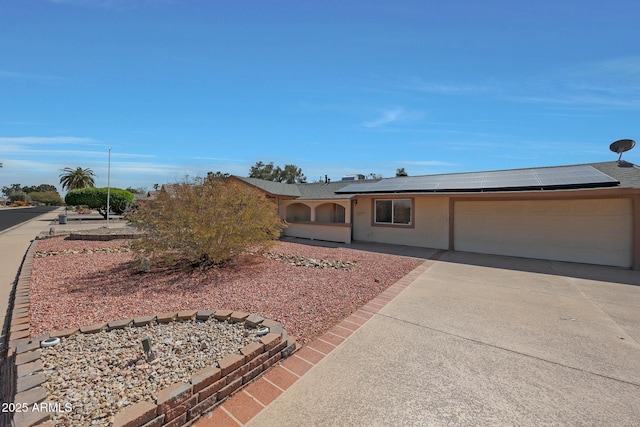 view of front of house featuring a garage, roof mounted solar panels, concrete driveway, and stucco siding