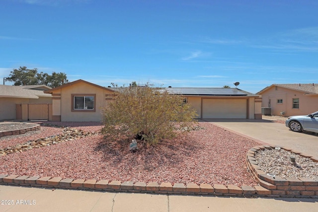 ranch-style home with roof mounted solar panels, stucco siding, driveway, and an attached garage