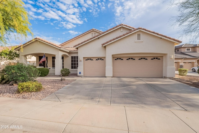 mediterranean / spanish-style house with a garage, concrete driveway, a tile roof, and stucco siding