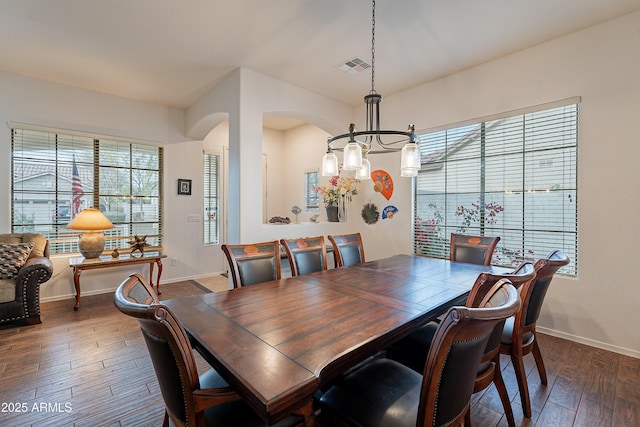 dining space with arched walkways, visible vents, dark wood finished floors, and baseboards