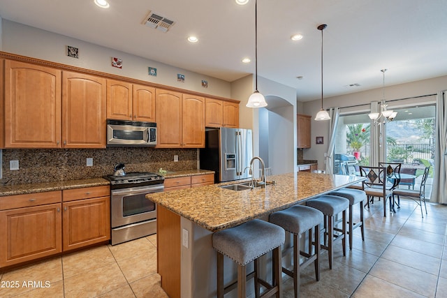 kitchen featuring stainless steel appliances, visible vents, decorative backsplash, a kitchen island with sink, and a sink