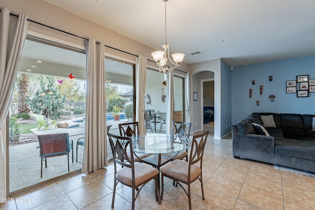 dining space featuring light tile patterned floors, visible vents, arched walkways, and a notable chandelier