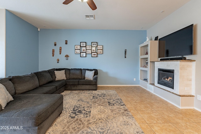 living room with visible vents, a tiled fireplace, ceiling fan, baseboards, and tile patterned floors