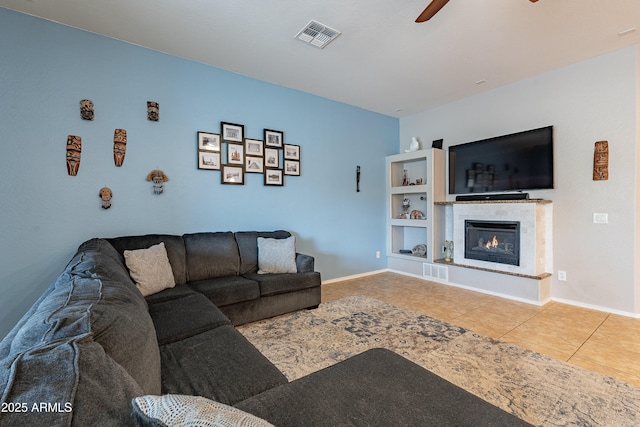 living area featuring a fireplace, a ceiling fan, baseboards, visible vents, and tile patterned floors