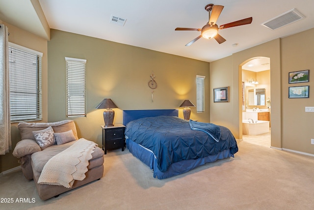 bedroom featuring arched walkways, carpet, ensuite bath, and visible vents