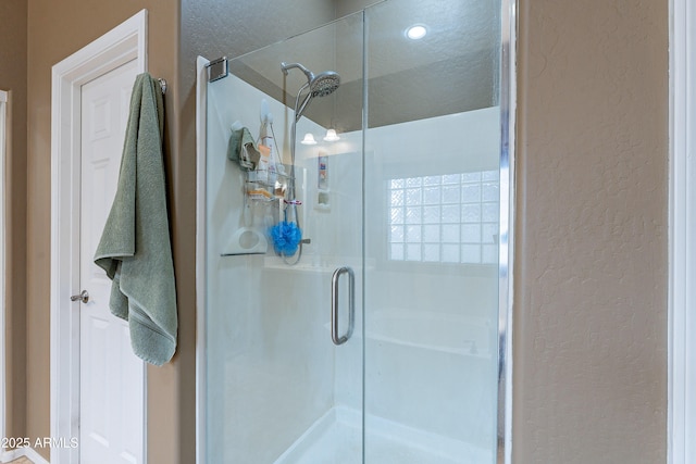 full bathroom with a textured wall and a stall shower