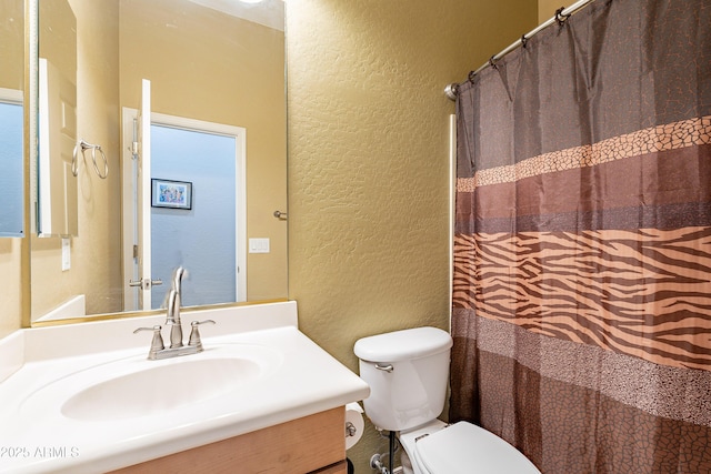 full bathroom featuring toilet, vanity, a shower with shower curtain, and a textured wall