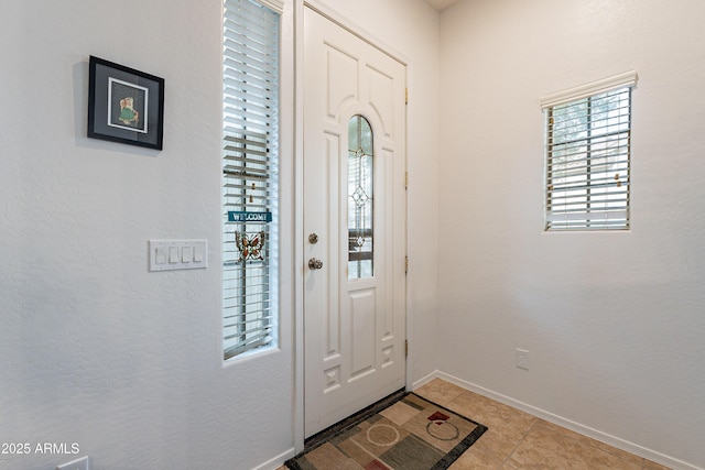 entryway with baseboards and light tile patterned flooring