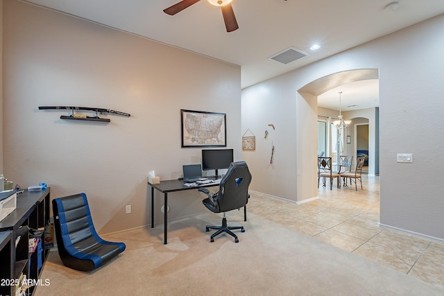 carpeted office with arched walkways, tile patterned flooring, ceiling fan with notable chandelier, visible vents, and baseboards