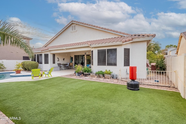 rear view of house with a patio, a fenced backyard, a tile roof, a lawn, and stucco siding