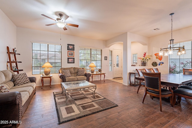 living room featuring arched walkways, ceiling fan with notable chandelier, wood finished floors, and visible vents