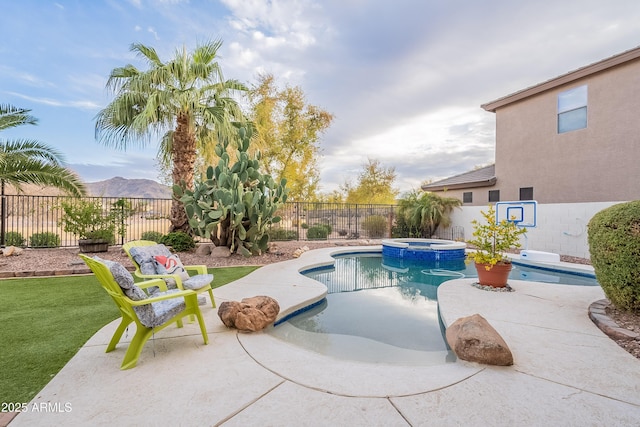 view of swimming pool featuring a pool with connected hot tub, a patio area, a fenced backyard, and a mountain view