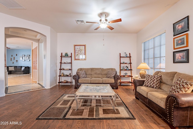 living room featuring arched walkways, wood finished floors, visible vents, and a ceiling fan