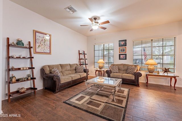 living room with dark wood-type flooring, visible vents, baseboards, and a ceiling fan