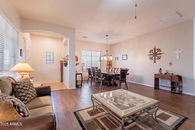 living area with arched walkways, visible vents, baseboards, and wood finished floors