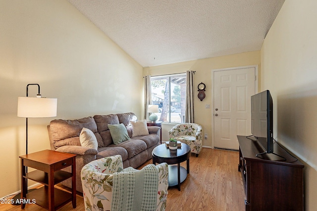 living room featuring a textured ceiling, vaulted ceiling, and light wood-type flooring