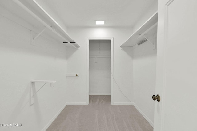 walk in closet with light carpet