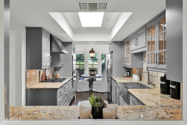 kitchen featuring a raised ceiling, gray cabinetry, and decorative backsplash