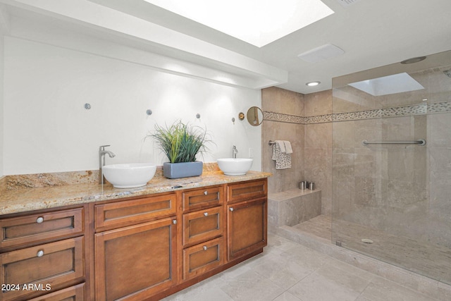 bathroom featuring tiled shower, vanity, a skylight, and tile patterned floors