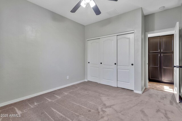 unfurnished bedroom featuring ceiling fan, light colored carpet, and a closet