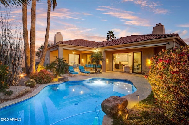 pool at dusk featuring a patio area