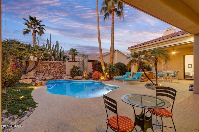 pool at dusk featuring a patio