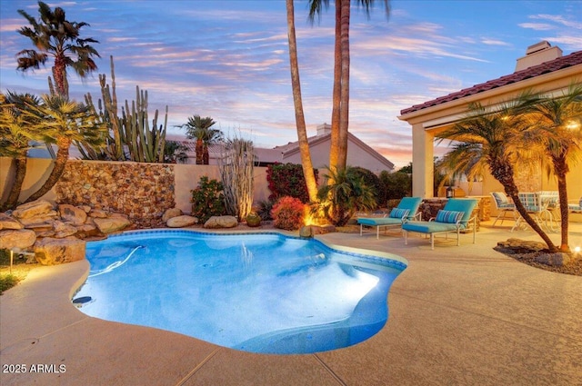 pool at dusk featuring a patio area