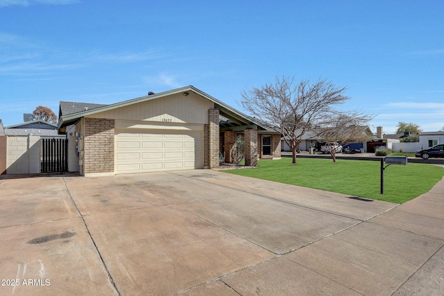 view of front of home featuring an attached garage, driveway, a front lawn, and brick siding