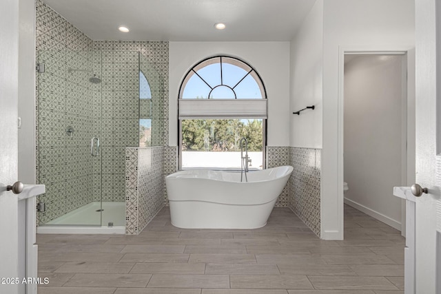 bathroom featuring plus walk in shower and tile walls