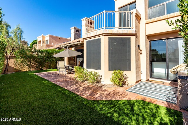 back of house with a patio, a balcony, and a lawn