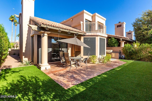 back of property with a yard, a balcony, and a patio area