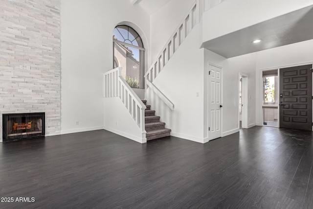 foyer entrance with beamed ceiling, a large fireplace, dark wood-type flooring, and high vaulted ceiling