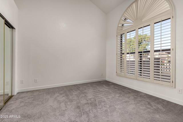 carpeted spare room with vaulted ceiling