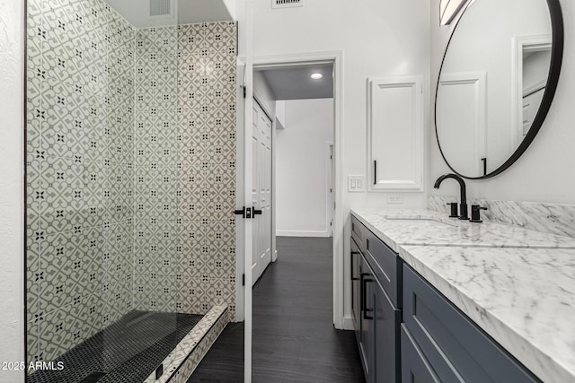 bathroom with tiled shower, vanity, and hardwood / wood-style flooring