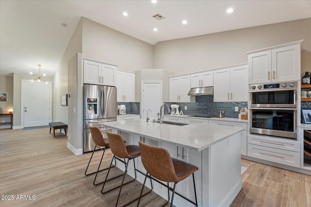 3604 E Derringer Way, Gilbert, AZ 85297 - kitchen featuring appliances with stainless steel finishes, under cabinet range hood, a sink, backsplash, and a kitchen island with sink