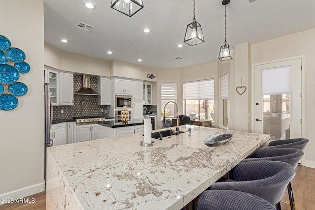 kitchen with white cabinetry, wall chimney exhaust hood, and a large island