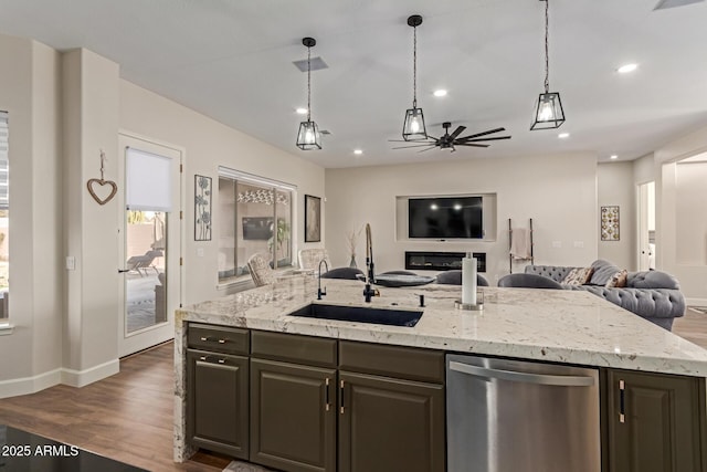 kitchen with stainless steel dishwasher, light stone countertops, sink, and a center island with sink